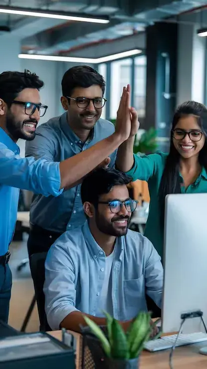 Smiling engineering team celebrating together at their desks
